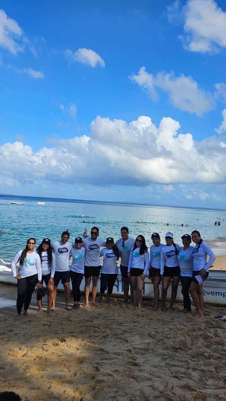 Equipe reunida junto a uma canoa na praia